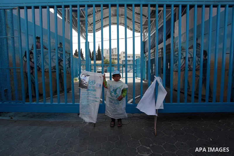 A Palestinian boy wears a sack of flour during a protest a the decision made by the United Nations Relief and Works Agency (UNRWA) to reduce food aid delivered to the Gaza Strip in front of the UNRWA headquarters in Gaza...