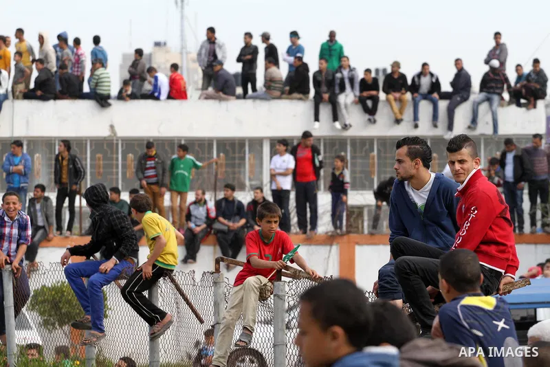 Palestinian fans of Rafah climb a fence as they watch their final soccer match against Shija'a in a local competition, at al-Yarmouk stadium in Gaza City April 11, 2014. Photo by Mohammed Asad