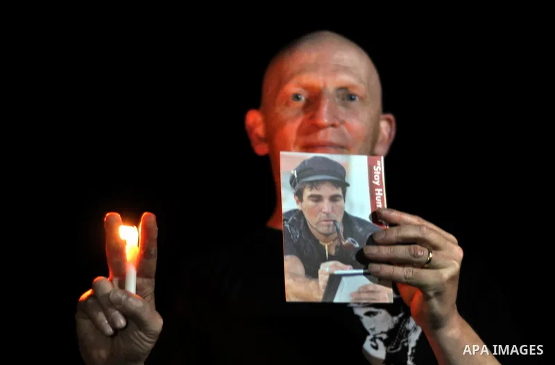 A foreign activist lights a candle and holds a picture of Italian human rights activist Vittorio Arrigoni during a rally marking the third anniversary of his murder, in Gaza City on April 15, 2014. Arrigoni, a 36-year-ol...