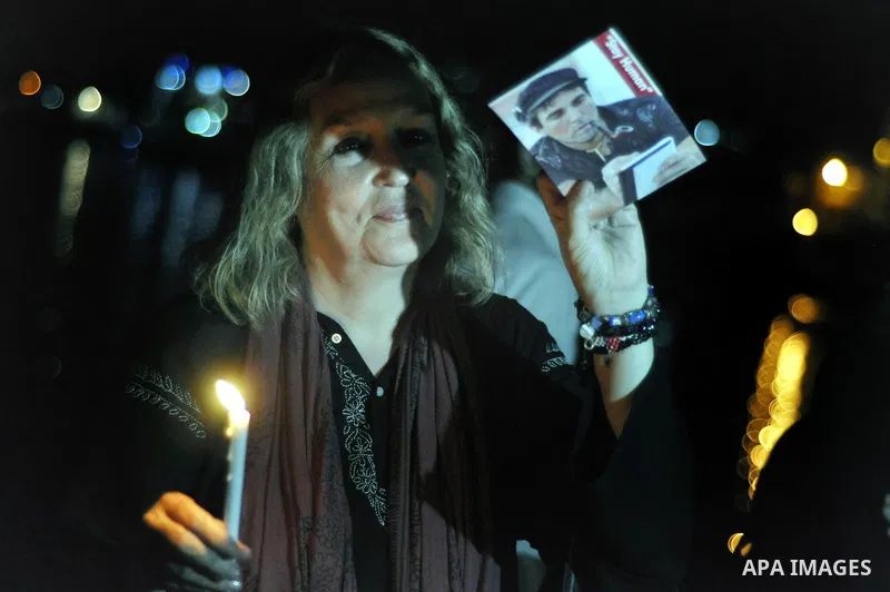A foreign activist lights a candle and holds a picture of Italian human rights activist Vittorio Arrigoni during a rally marking the third anniversary of his murder, in Gaza City on April 15, 2014. Arrigoni, a 36-year-ol...