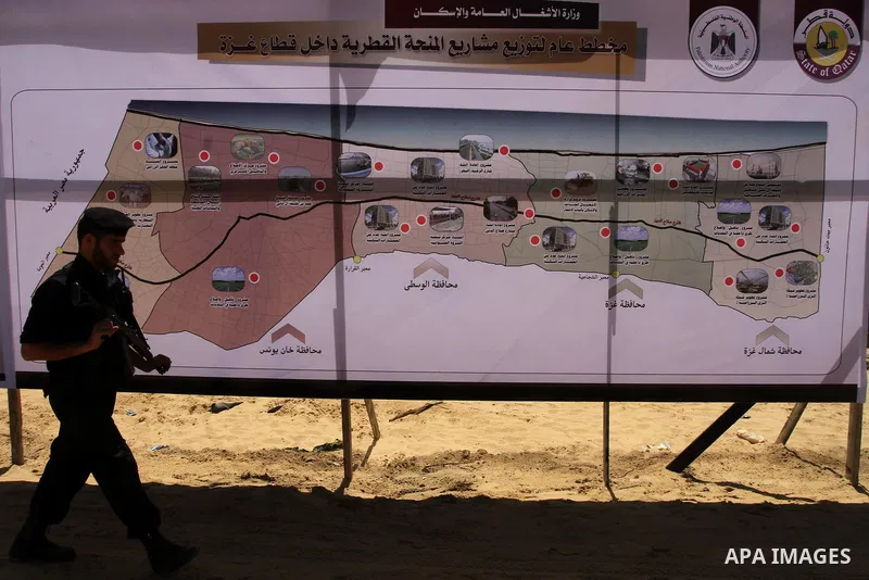 A Palestinian policeman walks past a map of Gaza Strip, at the construction site of al-Rasheed Road in Gaza City, April 16, 2014. Qatar funds several large economic projects in Gaza Strip ruled by Hamas, with the total c...