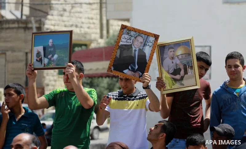 Palestinians hold pictures for the Palestinian prisoners in a rally marking Palestinian Prisoner's Day in the West Bank city of Tulkarem on April 17, 2014. Israel holds some 5,000 Palestinians it accuses of committing or...