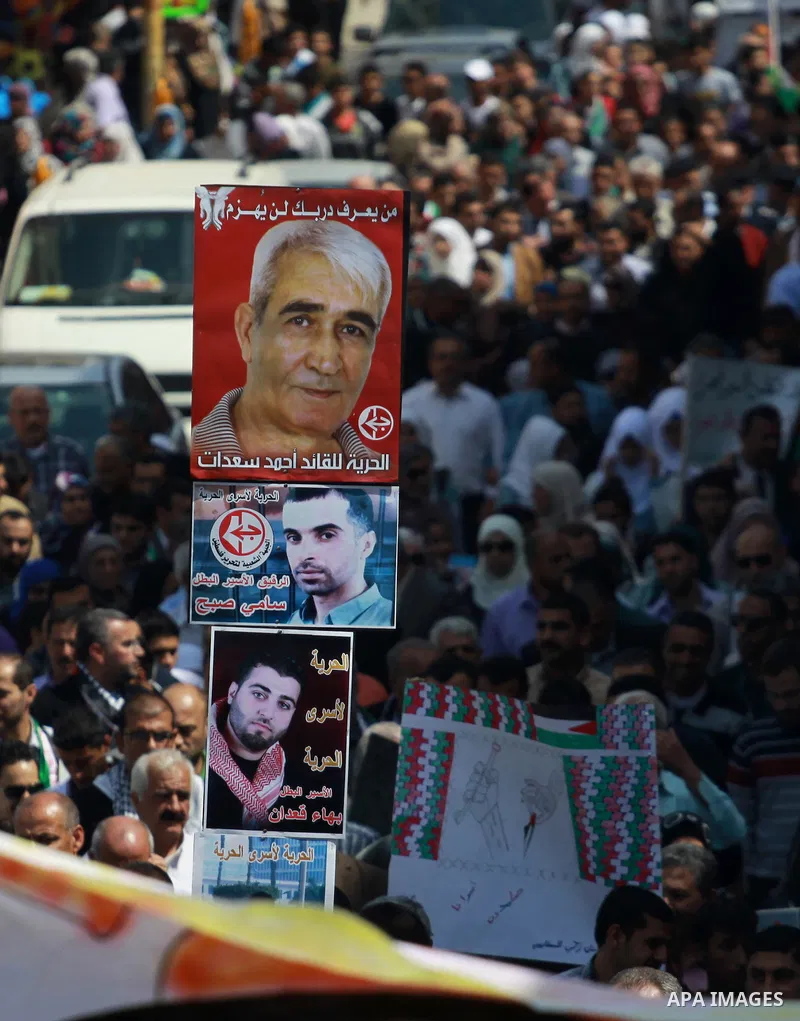Palestinians hold pictures for the Palestinian prisoners and national flags in a rally marking Palestinian Prisoner's Day in the West Bank city of Tulkarem on April 17, 2014. Israel holds some 5,000 Palestinians it accus...
