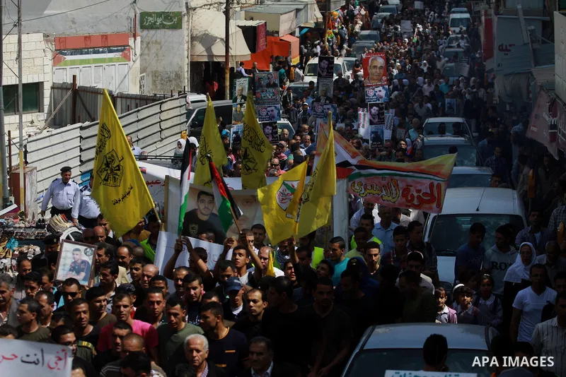 Palestinians hold pictures for the Palestinian prisoners and national flags in a rally marking Palestinian Prisoner's Day in the West Bank city of Tulkarem on April 17, 2014. Israel holds some 5,000 Palestinians it accus...