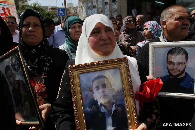 Palestinians hold pictures for the Palestinian prisoners and national flags in a rally marking Palestinian Prisoner's Day in the West Bank city of Tulkarem on April 17, 2014. Israel holds some 5,000 Palestinians it accus...