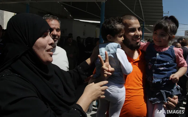 A Palestinian Fatah member gestures as he holds his daughters after his release from a Palestinian prison in Gaza City April 21, 2014. Palestinian ministry of interior in Gaza freed 10 prisoners of the rival Fatah moveme...
