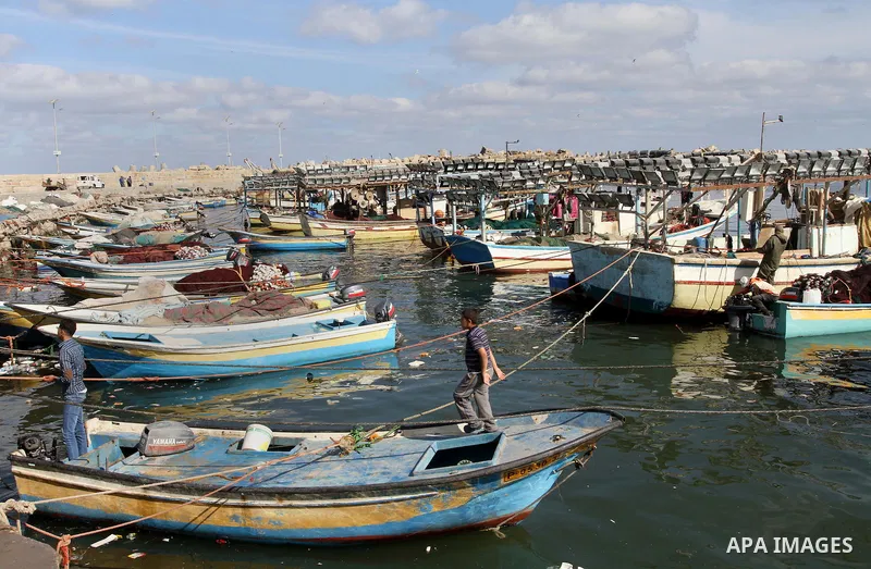 Palestinian fishermen work on their boat at the seaport in Gaza City on April 21, 2014. Photo by Mohammed Asad