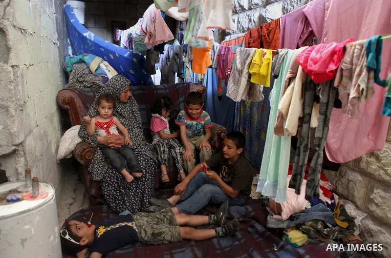 A Palestinian woman with her children inside thier house in Kafr near the West Bank city of Ramallah on April 25, 2014. Al-Kurdi poor family consist of 8 members who face difficult life and the high cost of living. Photo...