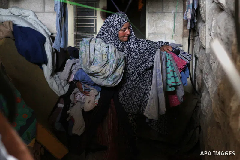 A Palestinian woman collects clothes inside thier house in Kafr near the West Bank city of Ramallah on April 25, 2014. Al-Kurdi poor family consist of 8 members who face difficult life and the high cost of living. Photo...