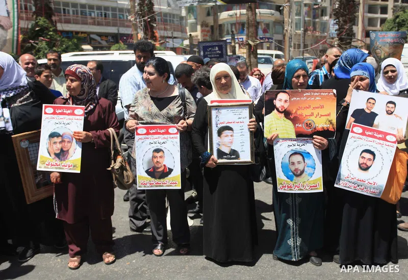 Palestinians hold pictures during a rally calling for the release of Palestinian prisoners from Israeli jails, in the West Bank city of RAmallah on April 28, 2014. Photo by Issam Rimawi