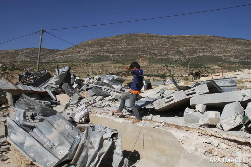 A Palestinian boy inspects the remains of a mosque after it was demolished by Israeli authorities who said it was built without municipal permission on April 29, 2014 in the West Bank village of Khirbet al-Tawil, south o...