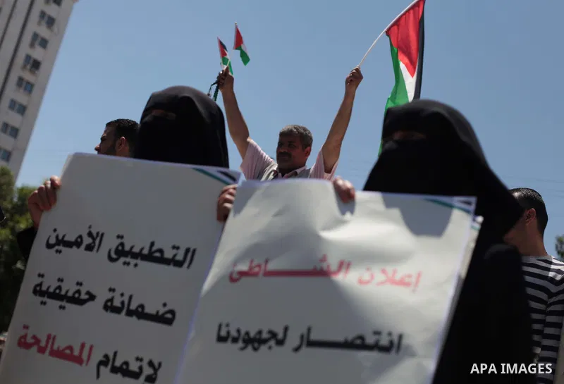 Palestinians hold placards and Palestine flags during a demonstration to calling for an end in the political division and the national reconciliation in Gaza city, on April 29, 2014. Photo by Ashraf Amra