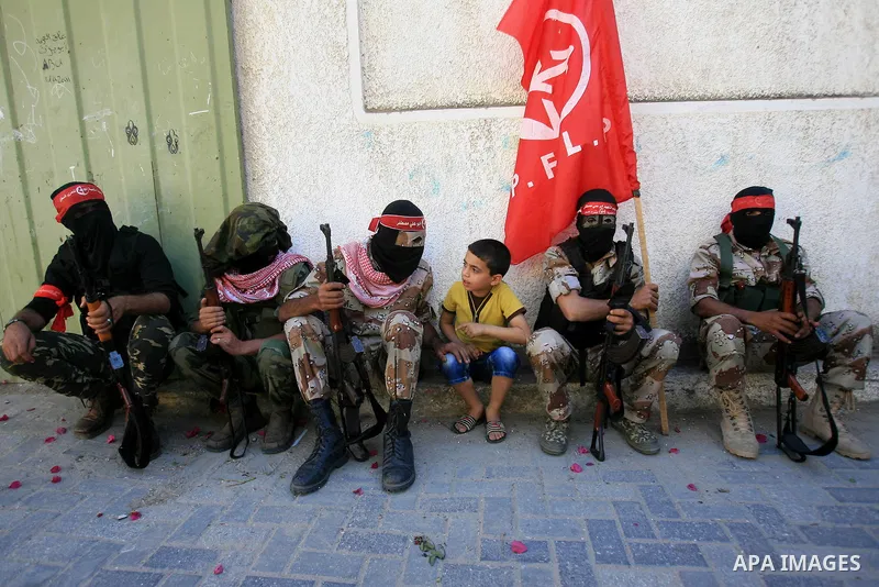A member of Palestinian militant from Popular Front for the Liberation of Palestine (PFLP) speaks with a boy during an anti-Israel parade in Khan Younis in the southern Gaza Strip, April 29, 2014. Photo by Eyad Al Baba