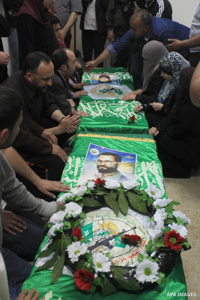 Palestinians gather around of the coffins of two Hamas members Adel and Imad Awadallah, killed in 1998, after their remains were returned from Israel in the early hours of April 30, 2014 in the West Bank city of Al-Bireh...