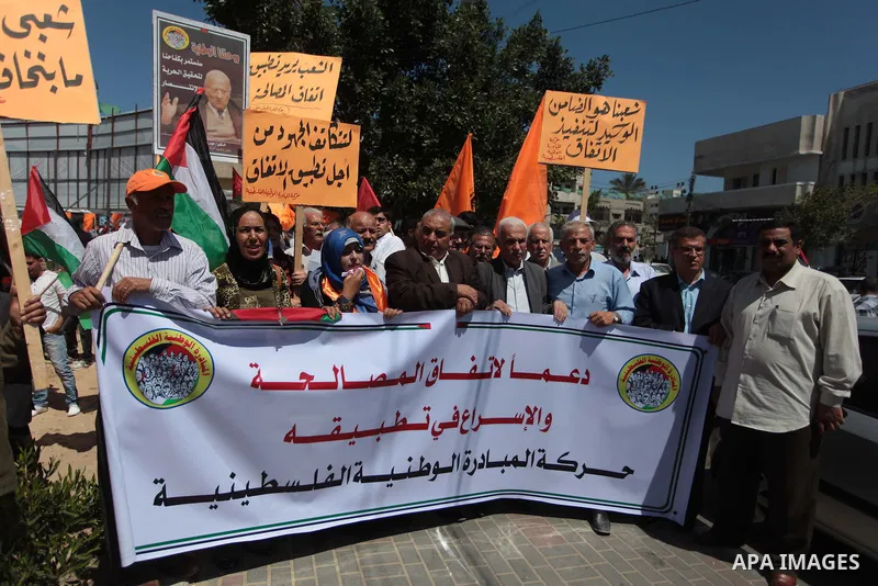 Palestinian National Initiative supporters hold placards and national flags during a demonstration to support the national reconciliation in Gaza city, on April 30, 2014. Photo by Ashraf Amra