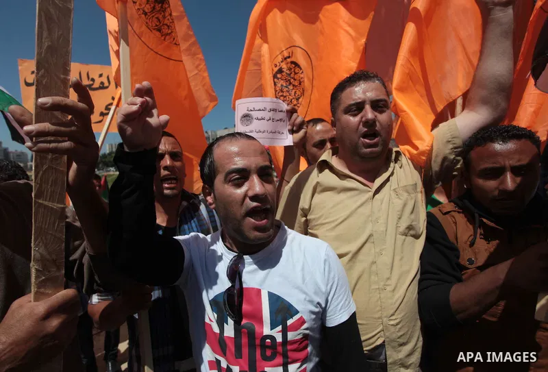Palestinian National Initiative supporters hold placards and national flags during a demonstration to support the national reconciliation in Gaza city, on April 30, 2014. Photo by Ashraf Amra