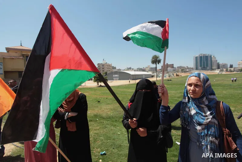 Palestinian National Initiative supporters hold placards and national flags during a demonstration to support the national reconciliation in Gaza city, on April 30, 2014. Photo by Ashraf Amra