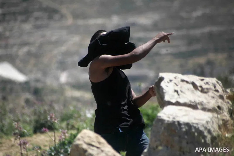 A Palestinian protestor throws stones towards members of the Israeli security forces during clashes in Al-Aroub refugee camp, near the West Bank City of Hebron April 30, 2014. Israeli military said that "security forces...