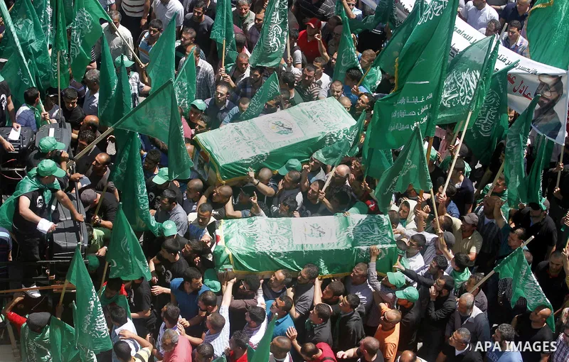 Palestinian mourners wave the green flag of the Islamist movement Hamas as they attend the funeral of two Hamas members, Adel and Imad Awadallah, killed in 1998, after Israel returned the remains of four Palestinians to...