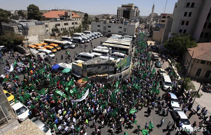 Palestinian mourners wave the green flag of the Islamist movement Hamas as they attend the funeral of two Hamas members, Adel and Imad Awadallah, killed in 1998, after Israel returned the remains of four Palestinians to...