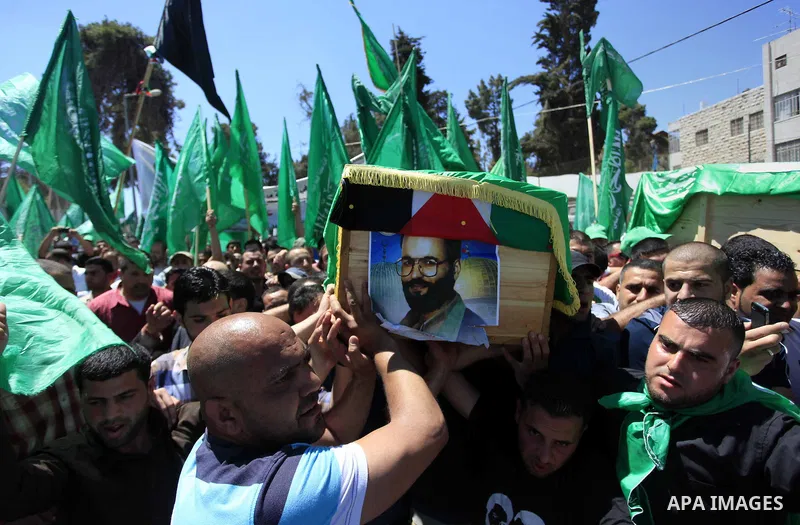 Palestinian mourners wave the green flag of the Islamist movement Hamas as they attend the funeral of two Hamas members, Adel and Imad Awadallah, killed in 1998, after Israel returned the remains of four Palestinians to...