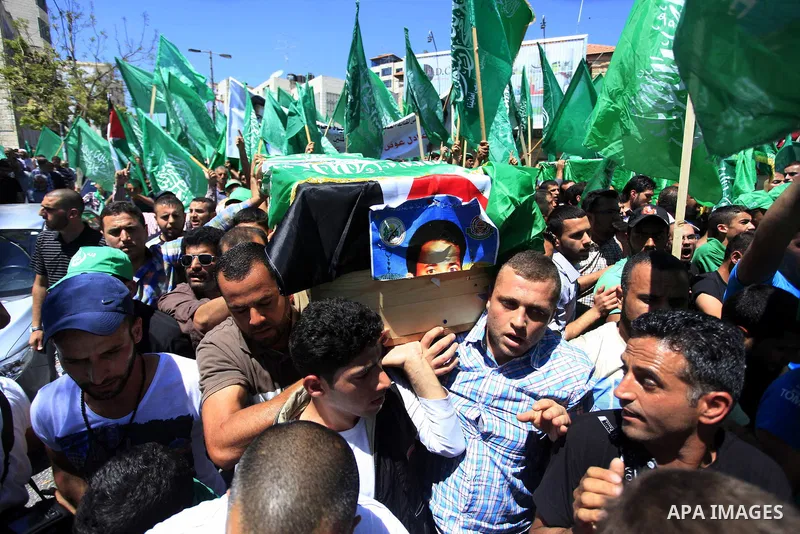 Palestinian mourners wave the green flag of the Islamist movement Hamas as they attend the funeral of two Hamas members, Adel and Imad Awadallah, killed in 1998, after Israel returned the remains of four Palestinians to...