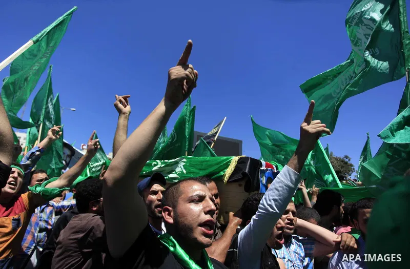 Palestinian mourners wave the green flag of the Islamist movement Hamas as they attend the funeral of two Hamas members, Adel and Imad Awadallah, killed in 1998, after Israel returned the remains of four Palestinians to...