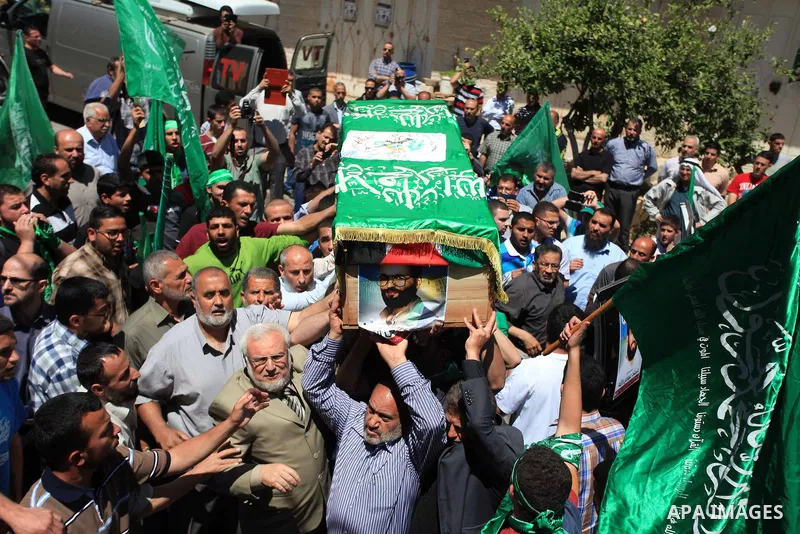 Palestinian mourners wave the green flag of the Islamist movement Hamas as they attend the funeral of two Hamas members, Adel and Imad Awadallah, killed in 1998, after Israel returned the remains of four Palestinians to...