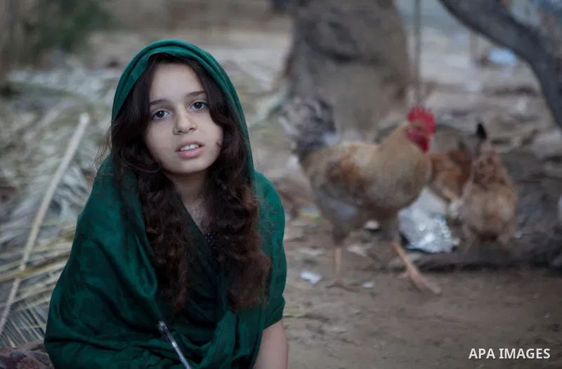 A Palestinian girl poses for a photograph as she plays outside her family's house, in the east of ‎Gaza‬ City near the border with Israel, May 1, 2014. Photo by Ezz Zanoun