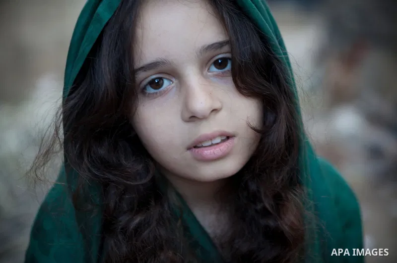 A Palestinian girl poses for a photograph as she plays outside her family's house, in the east of ‎Gaza‬ City near the border with Israel, May 1, 2014. Photo by Ezz Zanoun