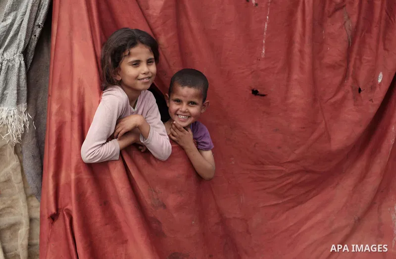 Palestinian Bedouin children look through a curtain as they play outside a shed near their family's house, in Gaza City on May 04, 2014. Photo by Ashraf Amra