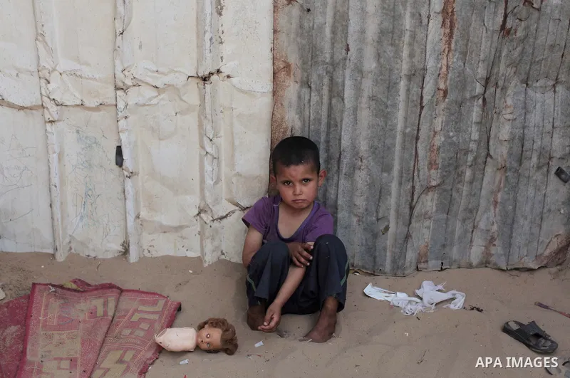 A Palestinian Bedouin boy plays outside a shed near his family's house, in Gaza City on May 04, 2014. Photo by Ashraf Amra