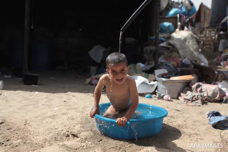 A Palestinian Bedouin boy bathes himself outside a shed near his family's house, in Gaza City on May 04, 2014. Photo by Ashraf Amra