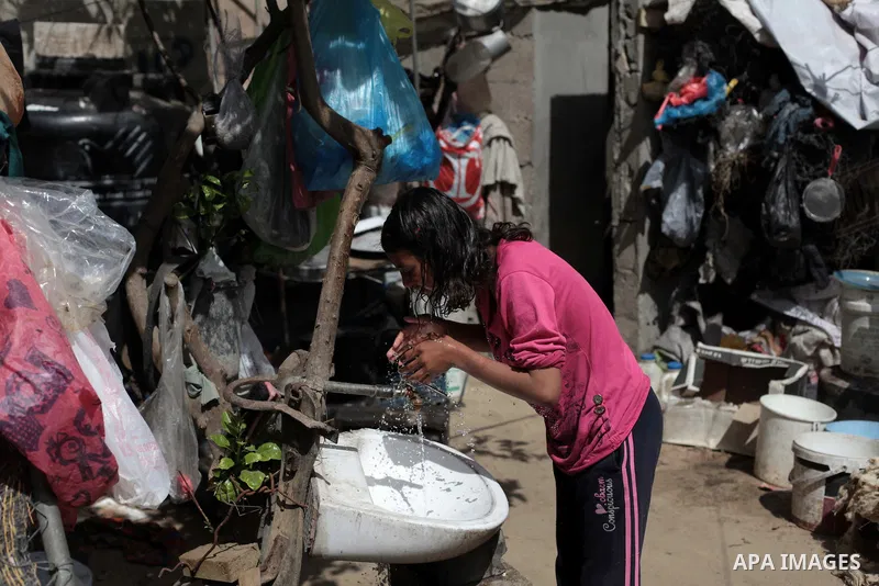 A Palestinian Bedouin girl washes her face outside a shed near their family's house, in Gaza City on May 04, 2014. Photo by Ashraf Amra