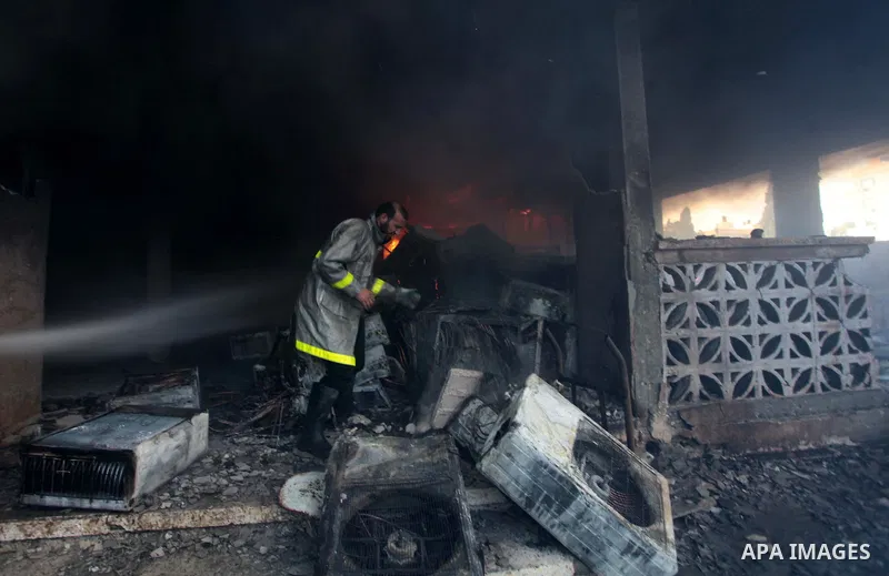 A Palestinian firefighter tries to extinguish a fire after a fire swept over a store of Electrical appliances in Gaza city on May 10, 2014. Photo by Ashraf Amra