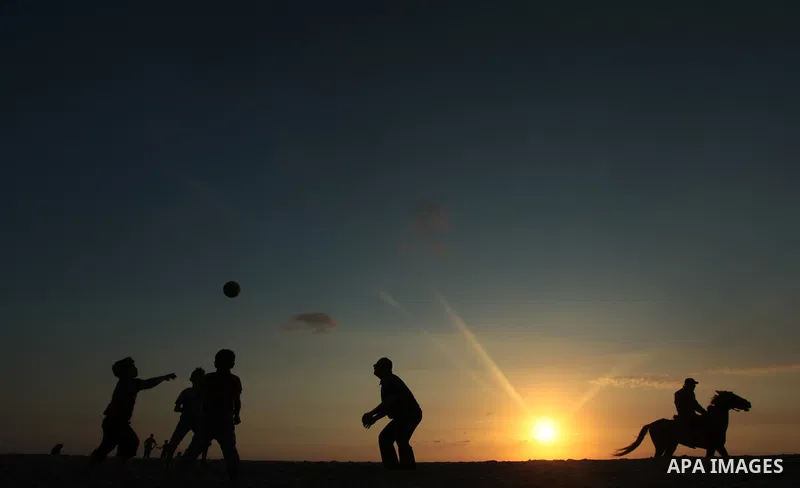 Palestinians enjoy playing during the sunset in the sea at Gaza beach on May 11, 2014. Photo by Yasser Qudih