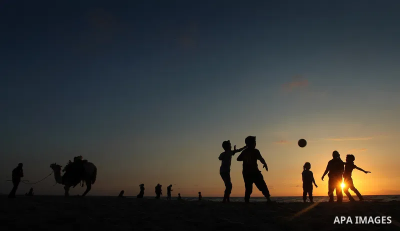 Palestinians enjoy playing during the sunset in the sea at Gaza beach on May 11, 2014. Photo by Yasser Qudih