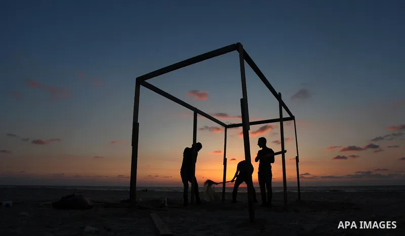 Palestinian youths build a tent in front of the sea at Gaza beach on May 11, 2014. Photo by Yasser Qudih