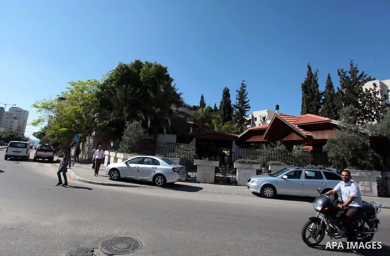 Palestinians walk past the house of Palestinian president Mahmoud Abbas in Gaza City May 14, 2014, as security forces prepare to handover the house which Hamas seized during a brief civil war with Fatah in 2007. Official...