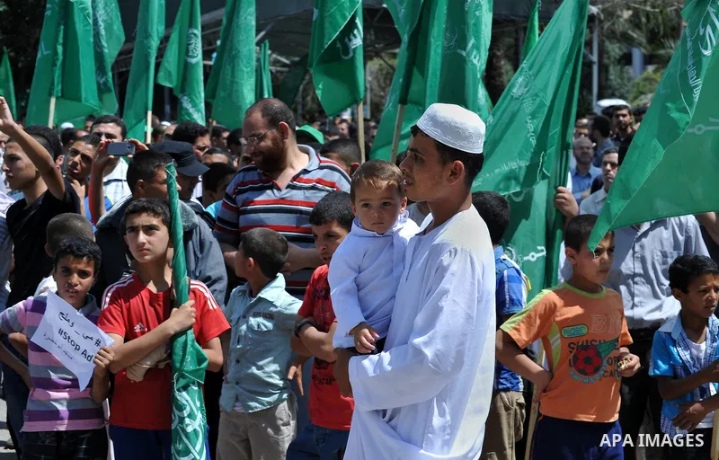 Palestinians hold banners during a demonstrator calling for the end of administrative detention as others wave their national flag in Gaza City on May 16, 2014 after Friday prayers to express solidarity with Palestinian...