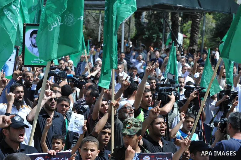 Palestinians hold banners during a demonstrator calling for the end of administrative detention as others wave their national flag in Gaza City on May 16, 2014 after Friday prayers to express solidarity with Palestinian...