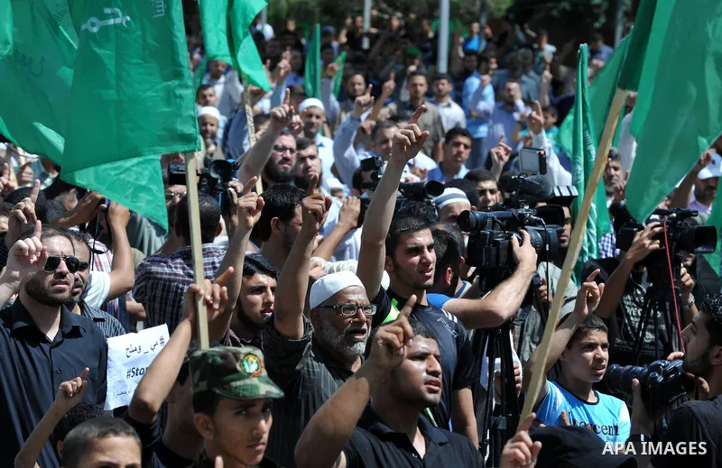 Palestinians hold banners during a demonstrator calling for the end of administrative detention as others wave their national flag in Gaza City on May 16, 2014 after Friday prayers to express solidarity with Palestinian...