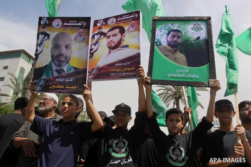 Palestinians hold banners during a demonstrator calling for the end of administrative detention as others wave their national flag in Gaza City on May 16, 2014 after Friday prayers to express solidarity with Palestinian...