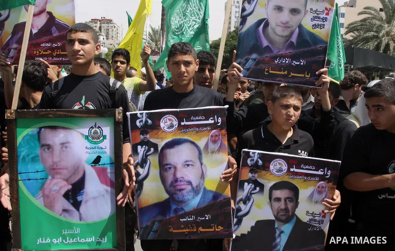 Palestinians hold banners during a demonstrator calling for the end of administrative detention as others wave their national flag in Gaza City on May 16, 2014 after Friday prayers to express solidarity with Palestinian...
