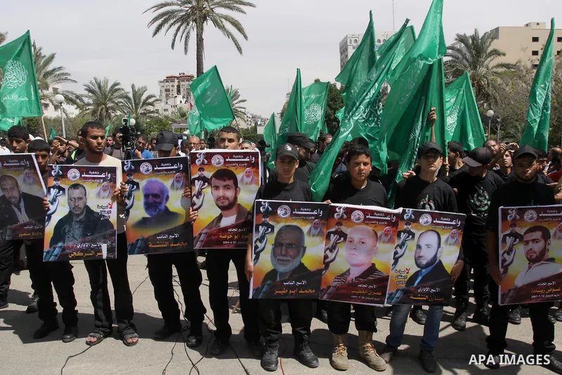 Palestinians hold banners during a demonstrator calling for the end of administrative detention as others wave their national flag in Gaza City on May 16, 2014 after Friday prayers to express solidarity with Palestinian...