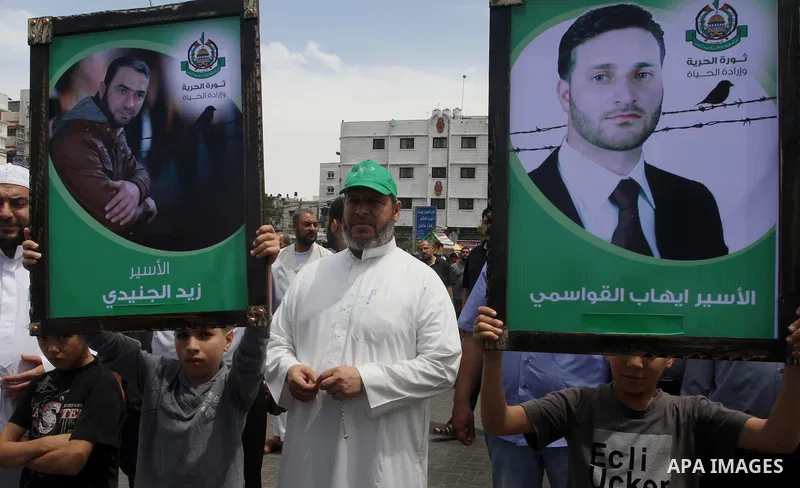 Palestinians hold banners during a demonstrator calling for the end of administrative detention as others wave their national flag in Gaza City on May 16, 2014 after Friday prayers to express solidarity with Palestinian...