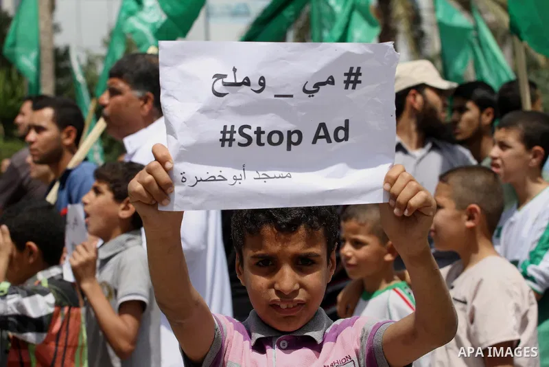 Palestinians hold banners during a demonstrator calling for the end of administrative detention as others wave their national flag in Gaza City on May 16, 2014 after Friday prayers to express solidarity with Palestinian...
