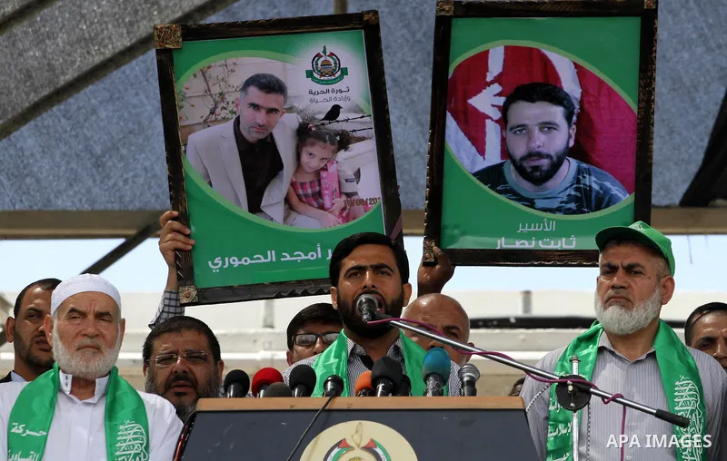 Palestinians hold banners during a demonstrator calling for the end of administrative detention as others wave their national flag in Gaza City on May 16, 2014 after Friday prayers to express solidarity with Palestinian...