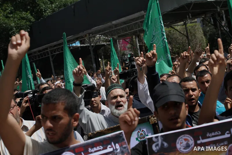 Palestinians hold banners during a demonstrator calling for the end of administrative detention as others wave their national flag in Gaza City on May 16, 2014 after Friday prayers to express solidarity with Palestinian...