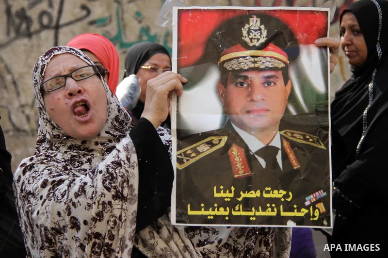 A Egyptian woman holds a picture of the Egypt's ex-army chief and leading presidential candidate Abdel Fattah al-Sisi outside a polling station in Cairo on May 26, 2014. Egyptians begin voting in a new presidential elect...